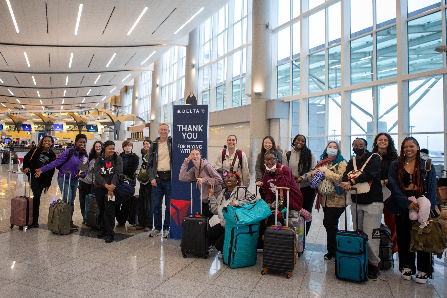 a group of students stand in an airport lobby