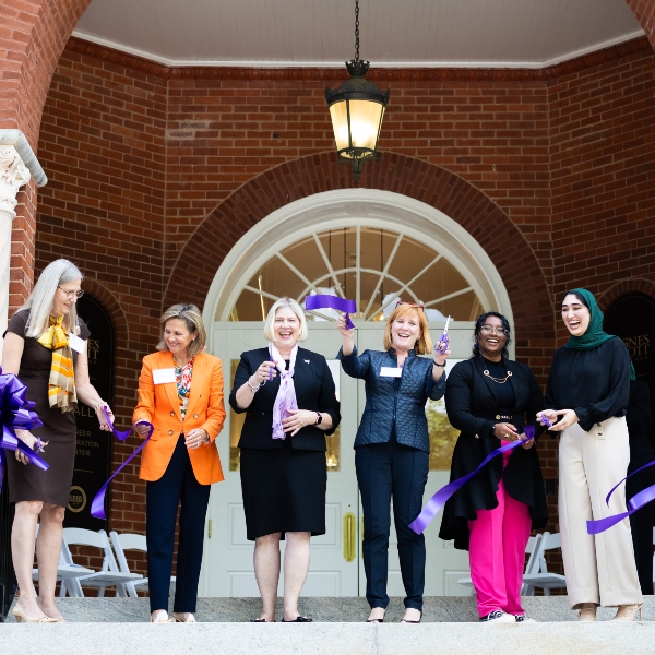 A group of people hold scissors in the air after a ribbon cutting for a renovated building