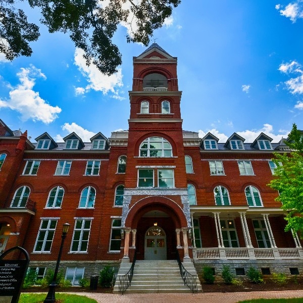 a straight on photo of Main Hall. The belltower stretches toward a blue sky with clouds