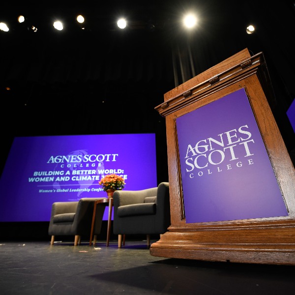 A podium with a purple Agnes Scott College banner sits on a stage