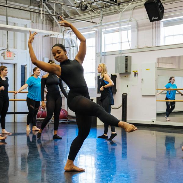 A dance major student performs in front of the class in a dance studio.