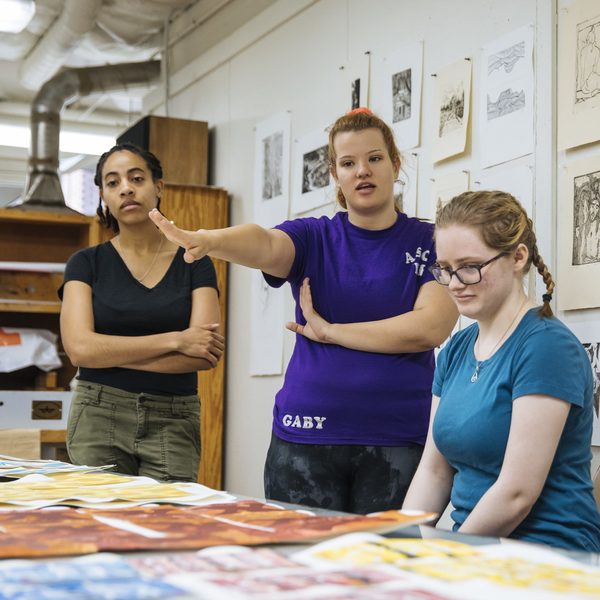 Three art history major students reviewing art work in class.