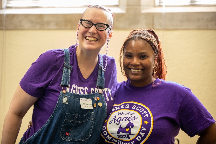 two people pose for a photo wearing purple shirts