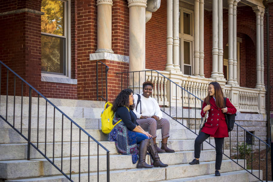 three students sitting on the steps of Main Hall