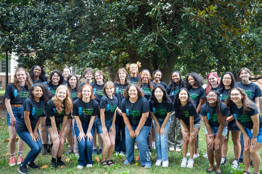 a group of student tutors gather on building stairs wearing the same branded black tee shirts